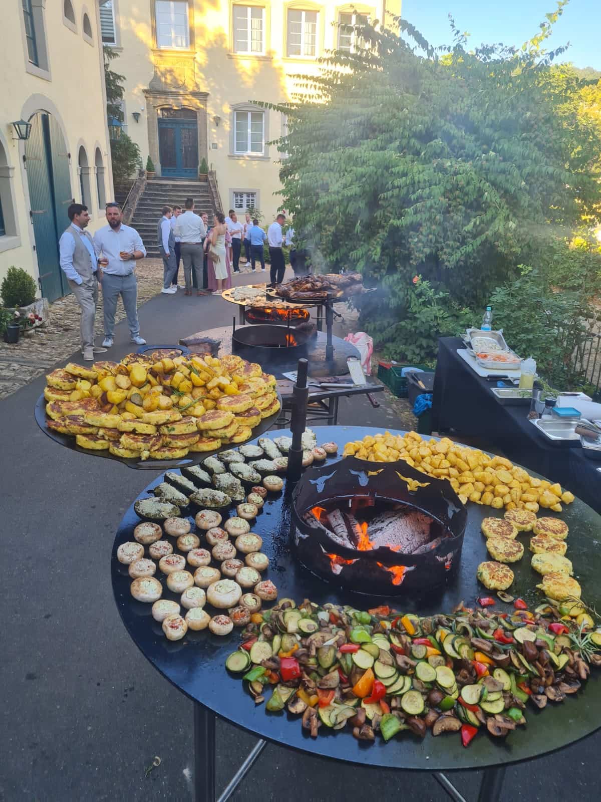 Grillbuffet mit Bratkartoffeln und Grillgemüse bei einem Gartenfest im Schlosshof