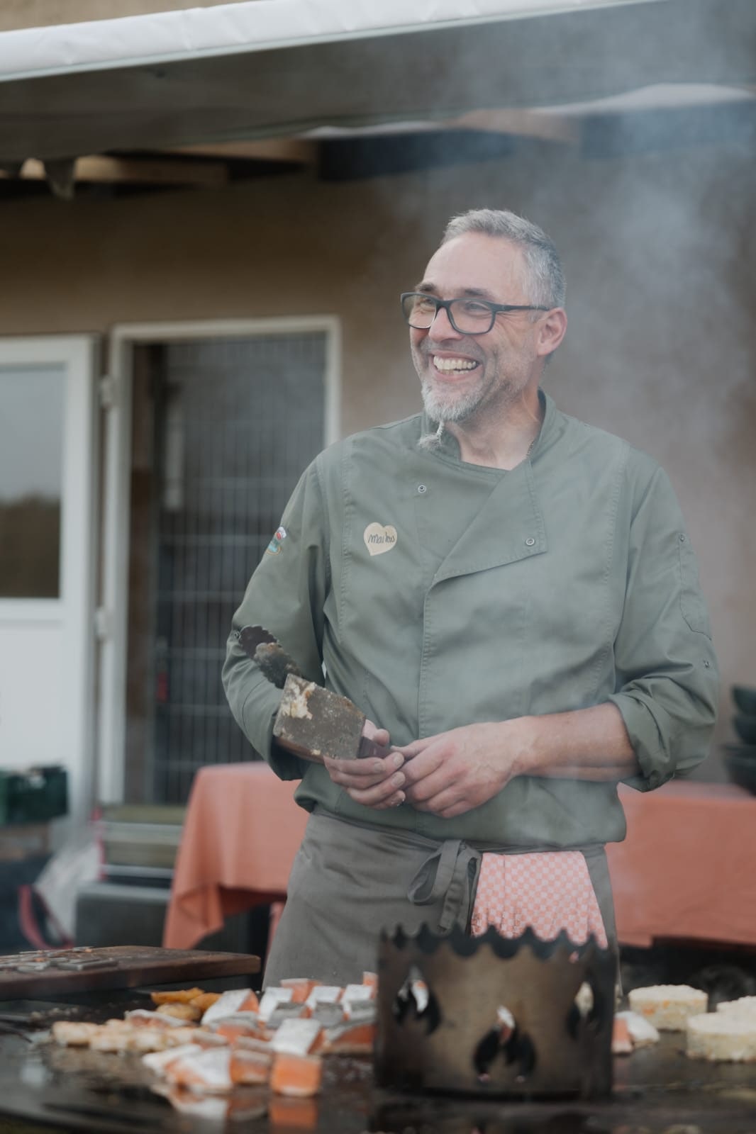 Küchenchef Maiko von Unter der Burg lächelnd an der Feuerplatte beim Grillen